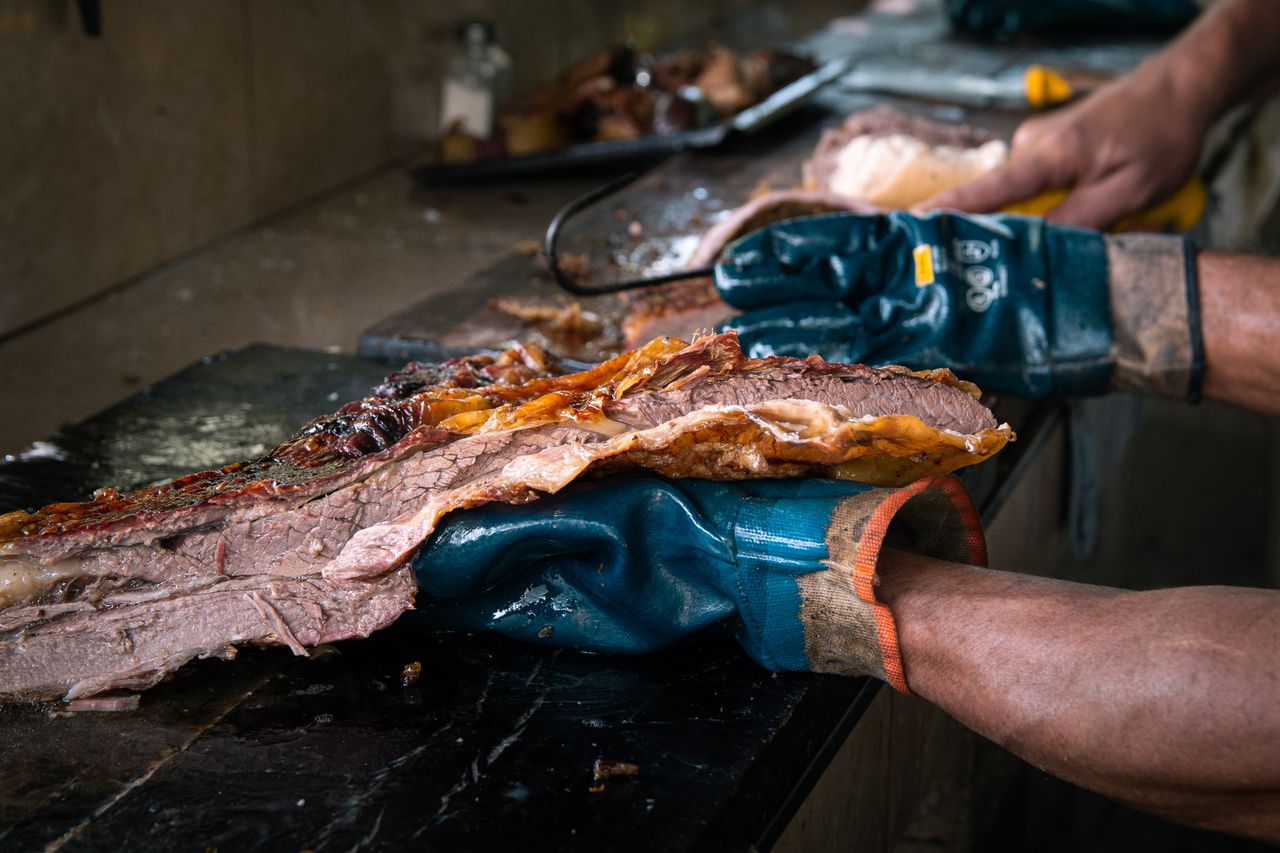 The Art of Drawing Readers In: Your attractive post title goes here Close-up of a gloved chef slicing a succulent, grilled beef brisket in a kitchen setting.
